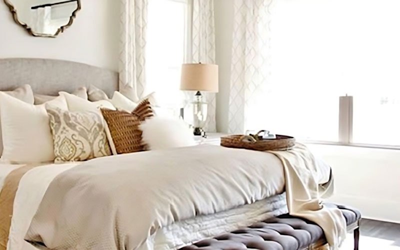 Photo of a bedroom decorated with light neutral colors and soft pillows and duvet cover